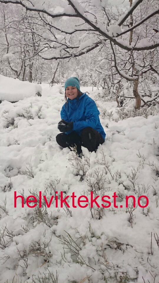 Eit bilete av ei dame kledd i blått som sit under eit tre i eit vinterlandskap.